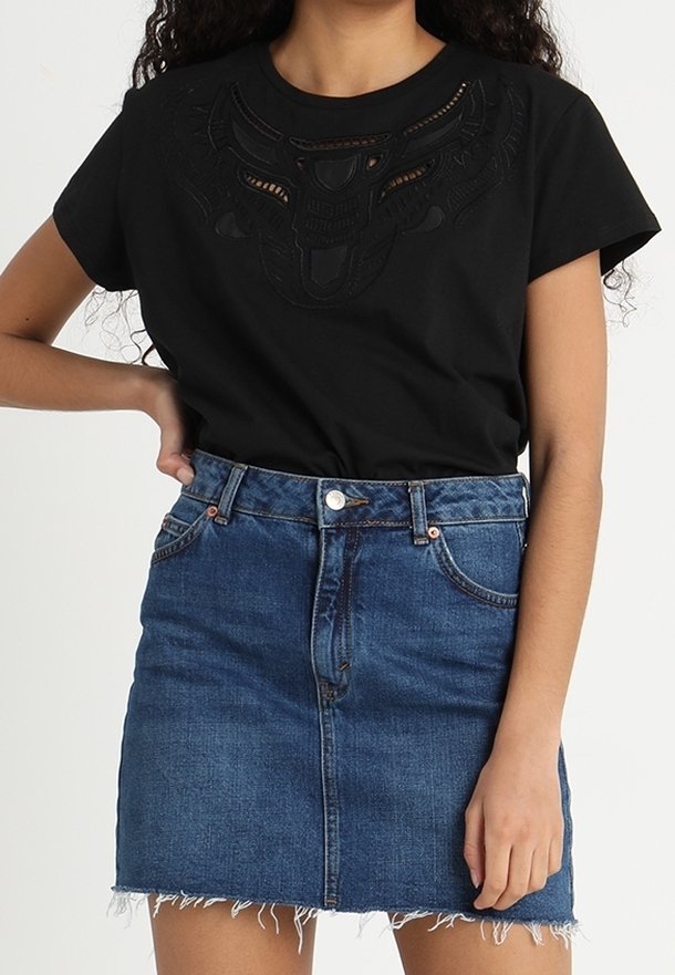 Svart kortärmad T-shirt med utskärningsdesign på framsidan; matchad med en högmidjad denim mini kjol med fransad fåll.