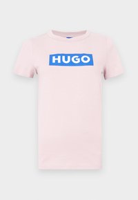 Lyserød bomuld T-shirt med korte ærmer, der har et hvidt "HUGO"-logo på en blå rektangulær baggrund på forsiden. Almindelig pasform, rund hals.