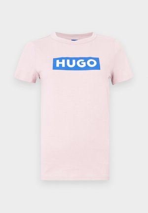 T-shirt en coton rose à manches courtes, avec un logo "HUGO" blanc sur fond rectangulaire bleu à l'avant. Coupe régulière, col rond.