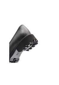 Semelle de chaussure en cuir noir avec une semelle épaisse et robuste conçue pour une meilleure adhérence et durabilité, vue sous un angle latéral bas.