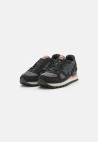 Schwarze und graue Sneakers aus Mesh- und Wildledermaterialien, mit einem pinken Logo auf der Zunge, einer strukturierten Sohle und einem gepolsterten Kragen.