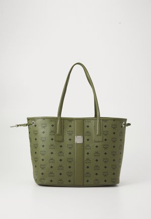 Grön läder tote-väska med svarta MCM-logotyper, långa handtag och en silverfärgad varumärkesplakett centrerad framtill.