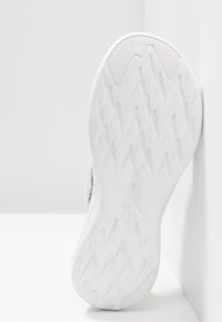 Suola di scarpa atletica bianca con un motivo di grip testurizzato e design angolari. Il materiale appare gommoso con una finitura liscia.