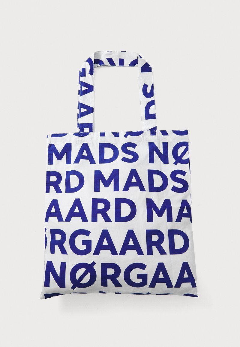 Sac cabas blanc avec des lettres bleues en gras répétant le motif "Mads Nørgaard", avec deux anses et une forme carrée.