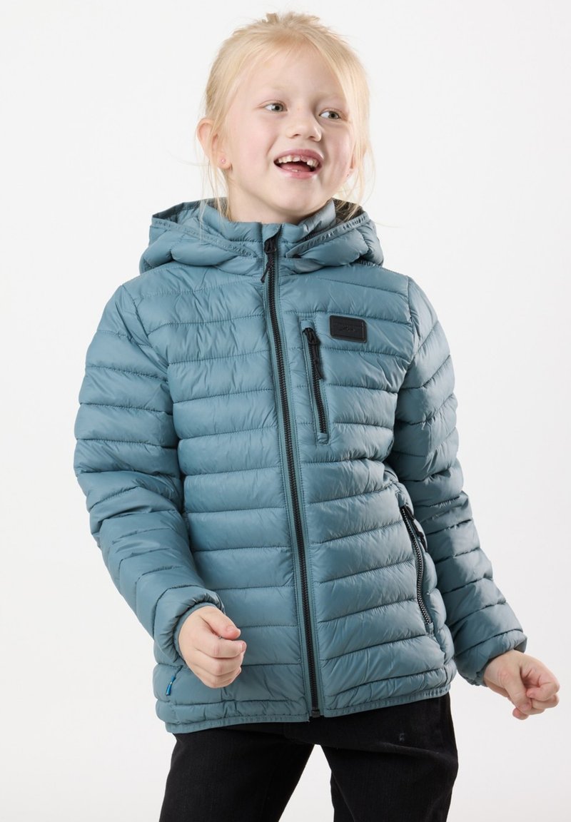 Blå dunjacka med huva, quiltad design, frontdragkedja och en bröstficka. Bärs över mörka byxor och visar en tajt passform.