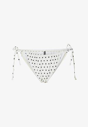 Valkoinen bikinihousu mustilla pallokuvioilla, sivusolmuiset, ja pieni musta merkkilappu etumaisen vyötärönauhan keskellä.