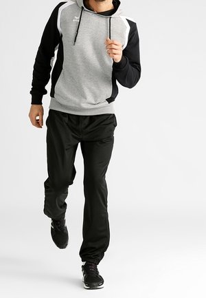 Felpa sportiva grigia e nera con tasca a marsupio, cappuccio e pantaloni neri. Il tessuto appare liscio e leggero.