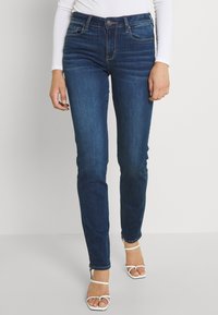 Dunkelblaue Jeans mit Slim Fit, leichter Ausbleichung an den Oberschenkeln, Fünf-Taschen-Design und kontrastierenden Nähten.