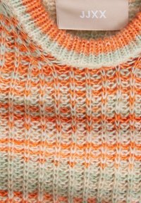 Pletený svetr s texturovaným vzorem v světle zelené barvě s oranžovými pruhy. Kulatý výstřih a štítek s nápisem "JJXX."