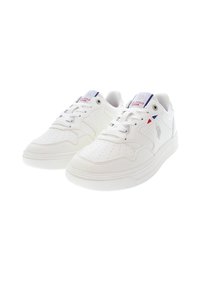 Vita sportskor med perforerad design, snören och rund tå. Har en logotyp på sidan och en vadderad sula för komfort.