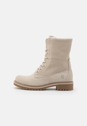 Bottines en suédine beige avec un design à lacets, bout rond, surface texturée et semelle en caoutchouc, dotées d'un accent logo sur le côté.