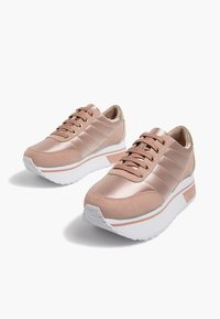 Baskets plateforme en or rose avec une finition satinée lisse, semelle blanche contrastante et coutures détaillées. Dotées de lacets plats et d'une languette rembourrée.