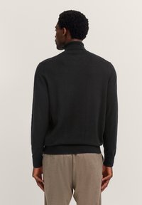 Schwarzer Rollkragenpullover aus glattem Stoff, mit einer figurschmeichelnden Passform, gerippten Bündchen und Saum für eine klare Silhouette.