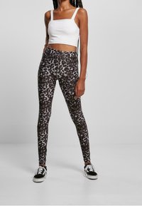 Höga leggings i ett svart och vitt abstrakt mönster, tillverkade av stretchigt tyg. Kombinerat med en åtsittande vit crop top och svarta sneakers.