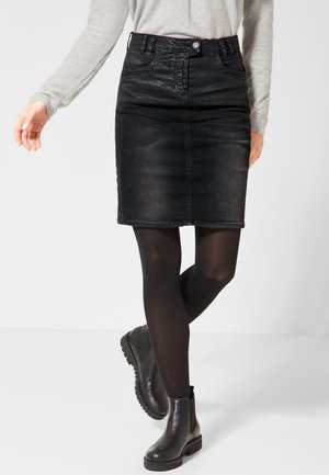 Jupe crayon en denim noir avec fermeture à boutons sur le devant, poches latérales, design mi-long, portée avec des collants opaques noirs et des bottines noires.