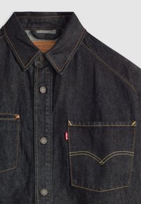 Donkerdenim shirt met knopen en een klassieke kraag, oranje stiksel, voorzakken en een Levi's logo label op de linker zak.