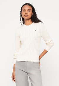 Sweterek w kolorze kremowym, wykonany na drutach, z wypukłym wzorem w diamenty, z prążkowanymi mankietami i dołem, z małym logo na lewej piersi.