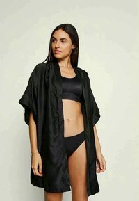 Svart satin kimono med korta ärmar, öppen front och en slät yta. Bärs över en matchande svart crop top och botten.