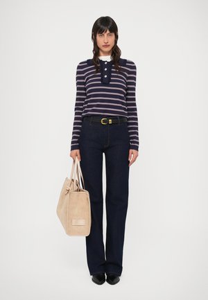 Top a maniche lunghe a righe blu navy con colletto smerlato, abbinato a jeans a gamba larga blu scuro e una borsa beige in camoscio. Scarpe nere con punta affilata.