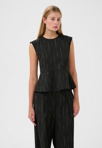 Czarny top peplum z fakturowanej tkaniny, z pionowymi złotymi kropeczkami, krótkimi rękawami i dopasowanym krojem, w zestawie z dopasowanymi spodniami.