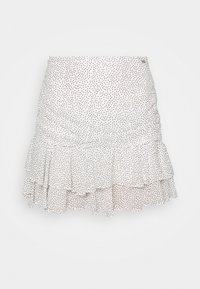 Jupe évasée blanche avec un design froncé, ornée de petits pois noirs. Fabriquée en tissu léger, avec une texture lisse.