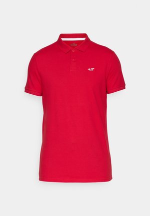 Rood katoenen poloshirt met een kraag, een knoopsluiting met twee knopen, korte mouwen en een klein wit logo op de linkerborst.