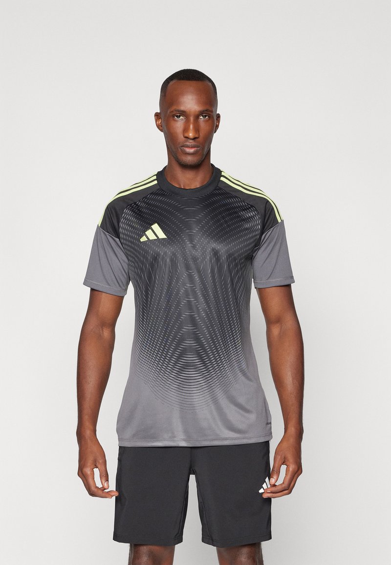 T-shirt de sport gris avec des accents noirs et des rayures jaunes sur les épaules. Présente un motif en vagues et des manches courtes. Assorti à un short noir.