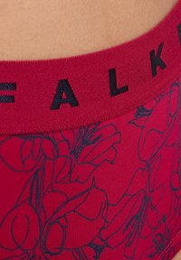 Czerwone majtki w wzory z kwiatowym motywem. Czarna elastyczna talia z napisem „FALK”. Tkanina wygląda na gładką i elastyczną.
