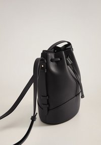 Sac seau noir en cuir lisse, doté de sangles réglables, d'un haut à cordon froncé et d'un design minimaliste.