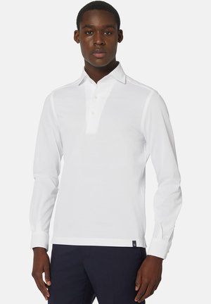 Langärmliges, weißes Polohemd aus glattem Material, mit einem geknöpften Kragen, geradem Saum und dezentem Branding unten links.