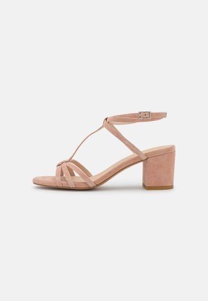 Sandale pour femme en daim rose blush avec talon carré, trois brides à l'avant et bride de cheville avec boucle argentée sur fond blanc.