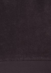 Temno vijolična brisača z mehko, teksturirano površino. Spodnji del ima gladek, kontrastni rob iz drugega materiala.