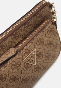 Portafoglio Guess marrone con motivo, dotato di cerniera dorata e distintivo metallico triangolare, vista ravvicinata inclinate.