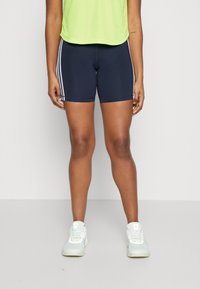 Námořnické sportovní šortky s bílými bočními pruhy, vyrobené z elastického materiálu. Spárované s světle zeleným topem a bílými teniskami s pastelovými akcenty.