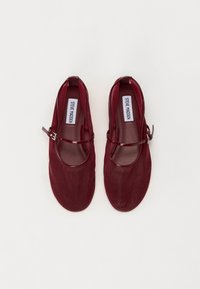 Ballerine Mary Jane bordeaux con finitura lucida, punta arrotondata e una sottile cinghia sul collo del piede. Rivestimento interno morbido e design minimalista.