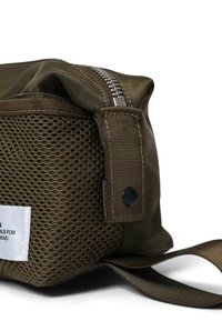 Brun stof tas med en struktureret mesh-side, sølv lynlås og en robust rem. Bemærkelsesværdige funktioner inkluderer et mærke og trykknapdetalje.