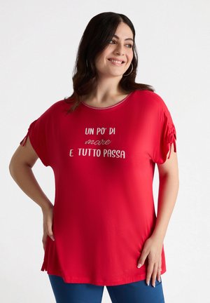 Top corto rojo de manga corta hecho de una tela suave, con un cuello redondo y un gráfico de texto. Las mangas tienen detalles fruncidos.