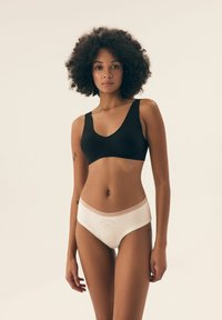 Czarny, gładki biustonosz bezszwowy z szerokimi ramiączkami; białe stringi z miękką gumką w pasie i napisem „kochaj siebie”. Gładki materiał, minimalistyczny design.