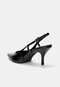 Escarpins en cuir verni noir à bride arrière, avec un bout pointu, une sangle de cheville réglable et un talon stiletto de 7 cm. Design simple avec une finition lisse.