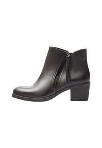 Botín de cuero negro con cremallera lateral y tacón bajo apilado, mostrado desde el lado exterior sobre un fondo blanco.