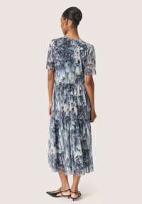 Pleated midi mekko sinisen ja harmaan sävyissä, lyhyet hihat, pyöreä kaula-aukko, kerrokselliset tasot, ilmava siluetti ja teräväkärkiset kengät.