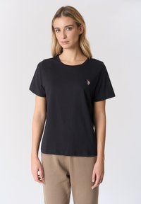 T-shirt in cotone nero con scollo rotondo e maniche corte, con un piccolo logo ricamato in oro nella zona sinistra del petto.