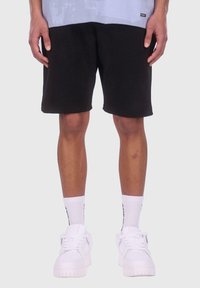Sorte bomuldsshorts med en afslappet pasform, parret med hvide sneakers og riflede hvide sokker med sorte detaljer.