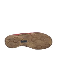 Red shoe with a textured leather upper and hexagonal rubber sole. Features a logo on the sole, providing traction.