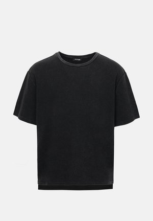 Μαύρο T-shirt με κοντά μανίκια, υφή βουνούφερο, με ριμπ λαιμόκοψη, εμφανιζόμενο σε απλό ανοιχτό γκρι φόντο.