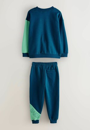 Marineblaue Sweatshirt mit grünen Ärmeln und passenden Jogginghosen. Die Sweatpants haben ein diagonales grünes Paneel mit dem eingeprägten Schriftzug "BAKER". Weicher Stoff, lässiges Design.