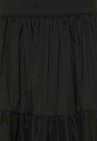 Robe noire présentant un design froncé et à étages avec une texture lisse. Fabriquée à partir d'un matériau léger et fluide. Aucun accessoire ou ornement visible.