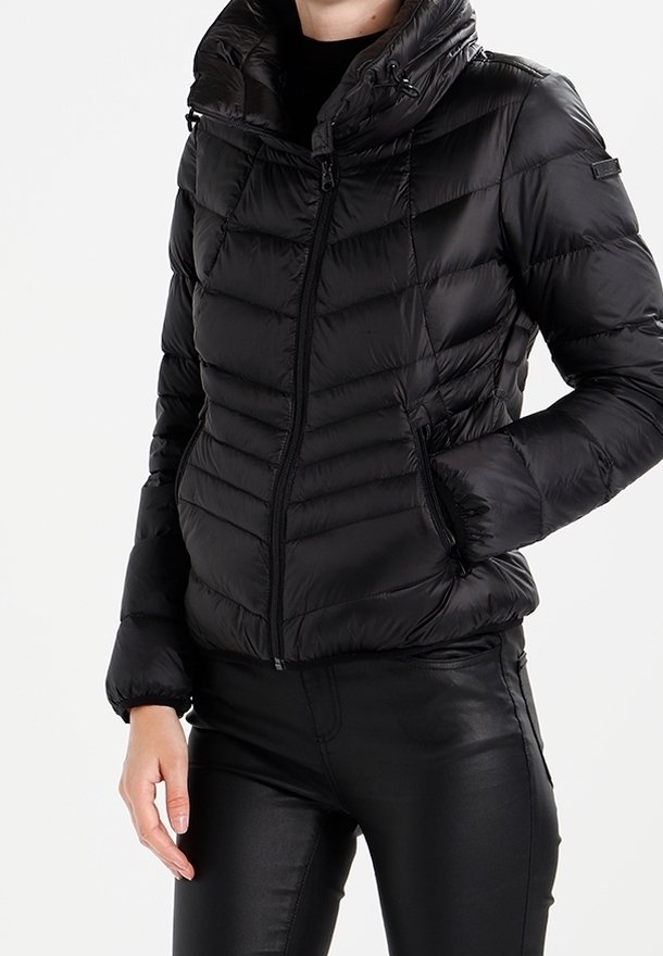 Mustapuffatakki, jossa on vetskarilla varustettu etuosa, korkea kaulus ja vaakasuuntainen tikkauskuvio. Sisältää sivutaskut ja elastiset hihnat.