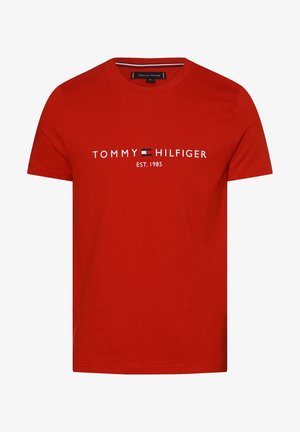 Czerwona bawełniana koszulka z krótkim rękawem, z logo "TOMMY HILFIGER" oraz napisem "EST. 1985" w kontrastującej bieli i małym niebiesko-czerwonym emblematem.