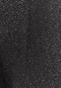 Svart tyg med en strukturerad yta som har subtila metalltrådar, vilket skapar en glittrande effekt genom materialet.